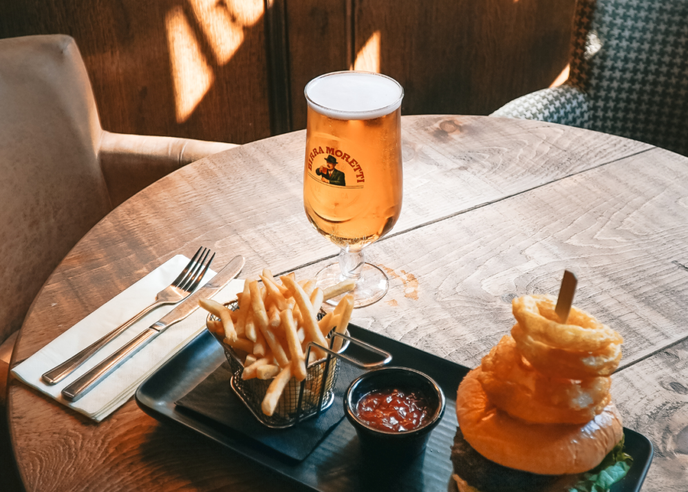 A delicious pint of Moretti beer paired with a mouthwatering burger at The Railway, a popular pub in East Grinstead.